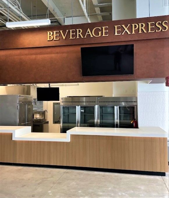 A Beverage Express service counter featuring a white countertop, wood paneling, and large stainless steel refrigerators.
