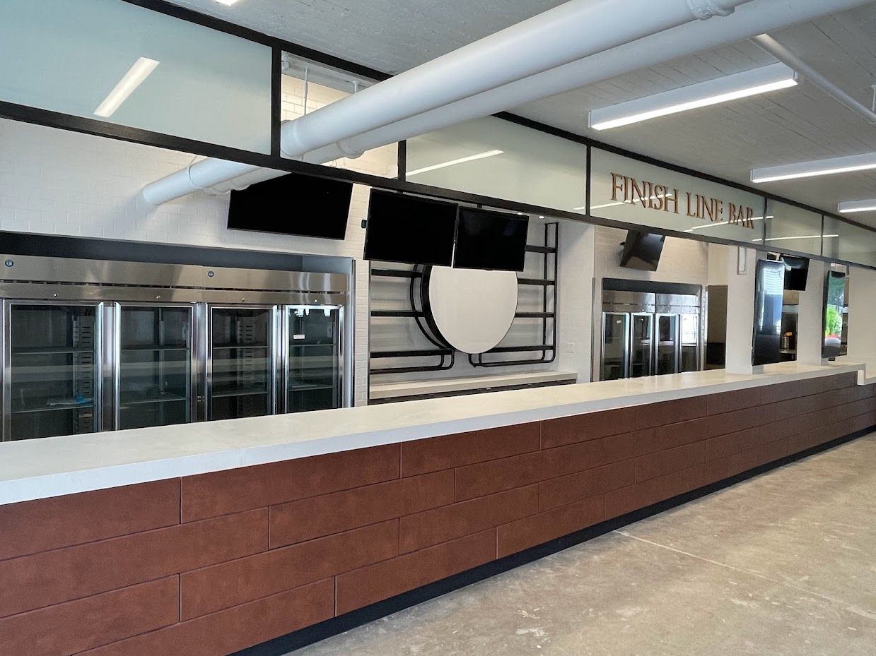 A long service bar with a brown brick counter, stainless steel refrigerators, and 