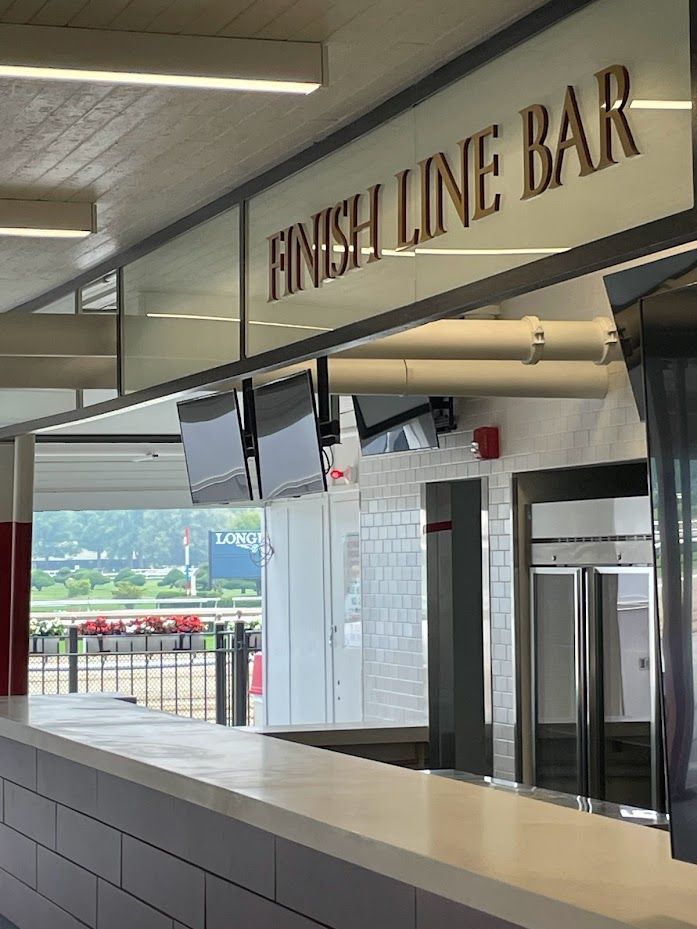A view of the Finish Line Bar at a racetrack, showing the service counter, monitors, and the track in the background.