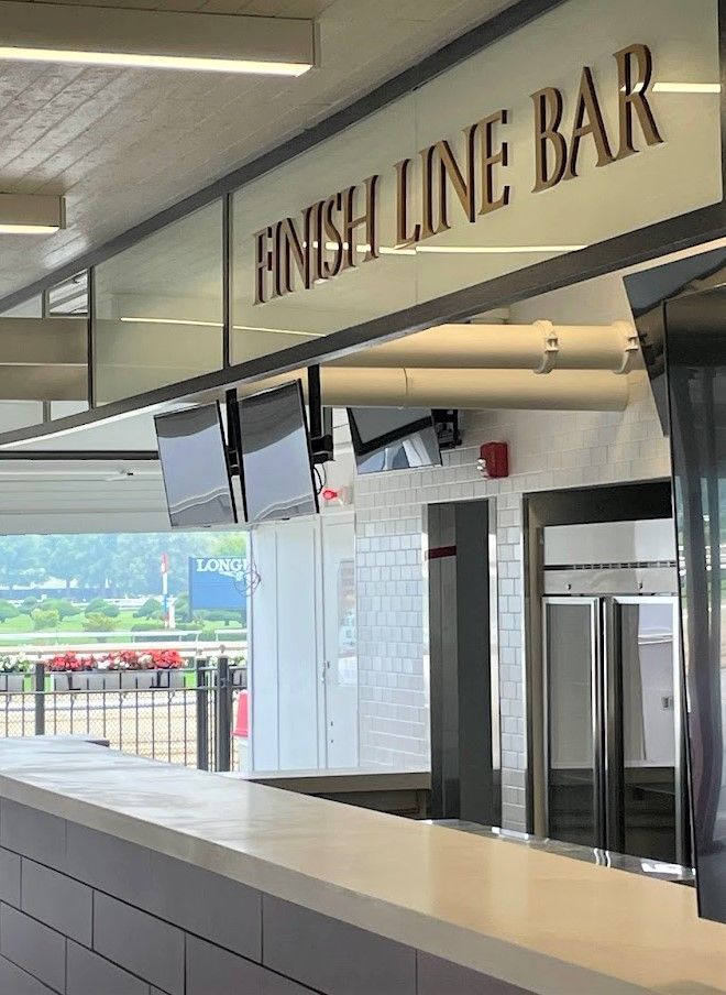 The Finish Line Bar with a white counter and tiled walls, overlooking an outdoor racetrack area.