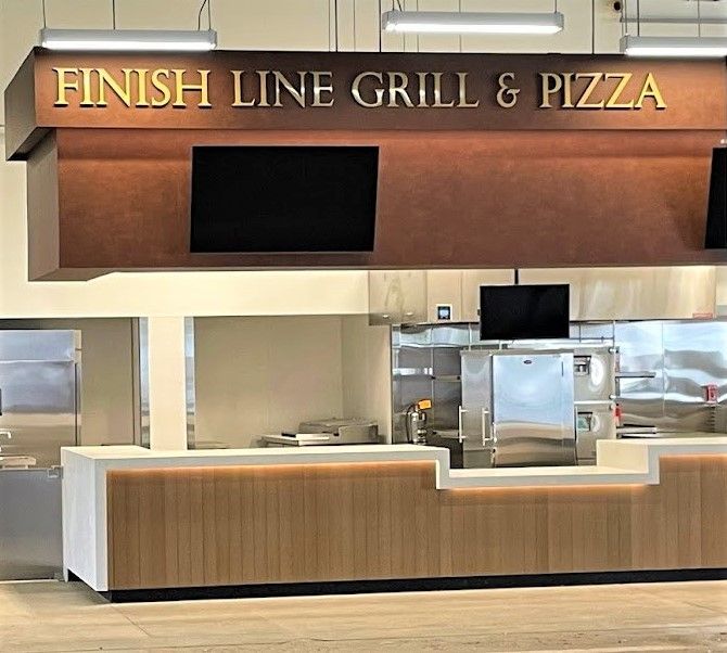 Finish Line Grill & Pizza food counter with a dark brown overhead sign, warm wood paneling, and a white service counter.