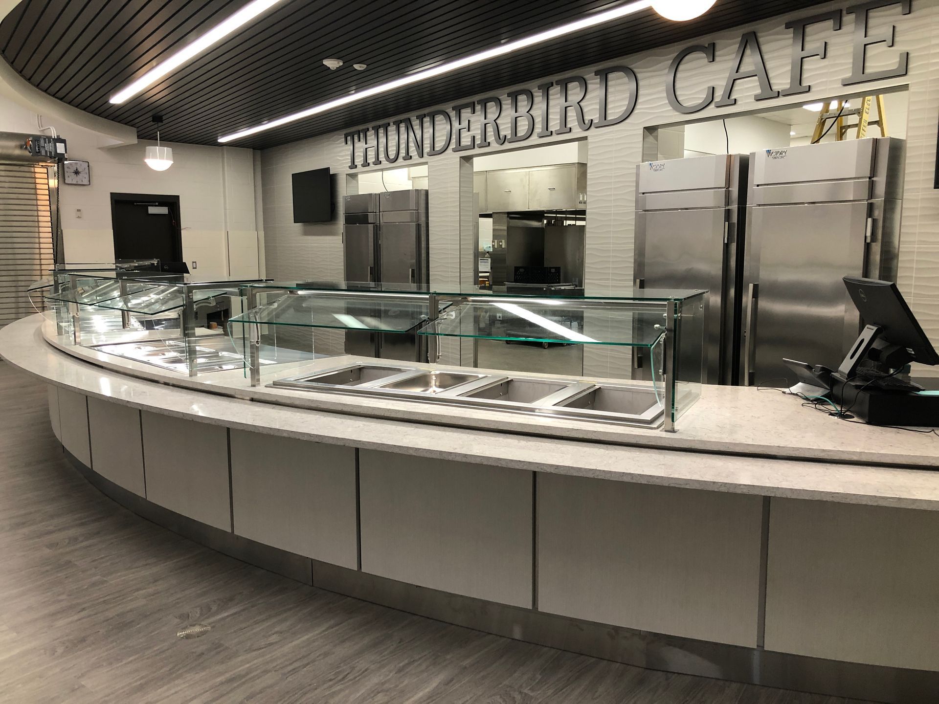 A curved service counter with food prep wells, glass sneeze guards, and 