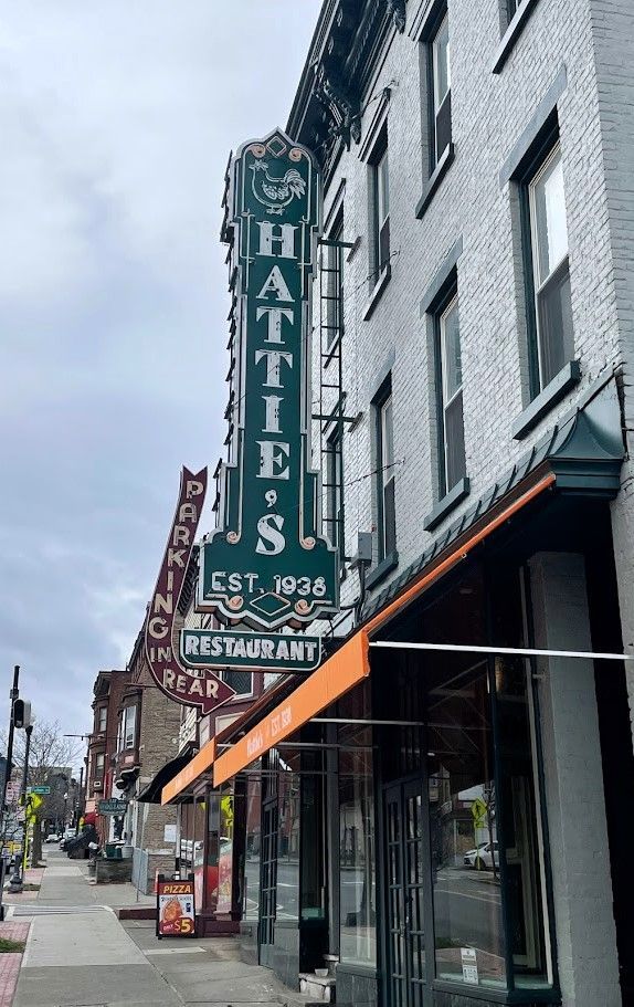 Vertical sign for Hattie's Restaurant, established 1935, on a gray brick building with an orange awning.