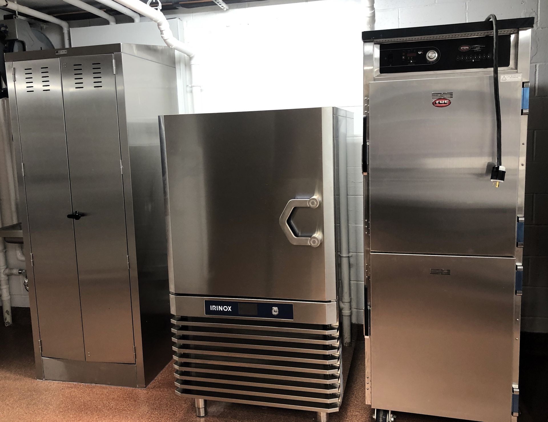 Three stainless steel kitchen appliances, including a tall storage unit, a blast chiller, and a commercial oven.