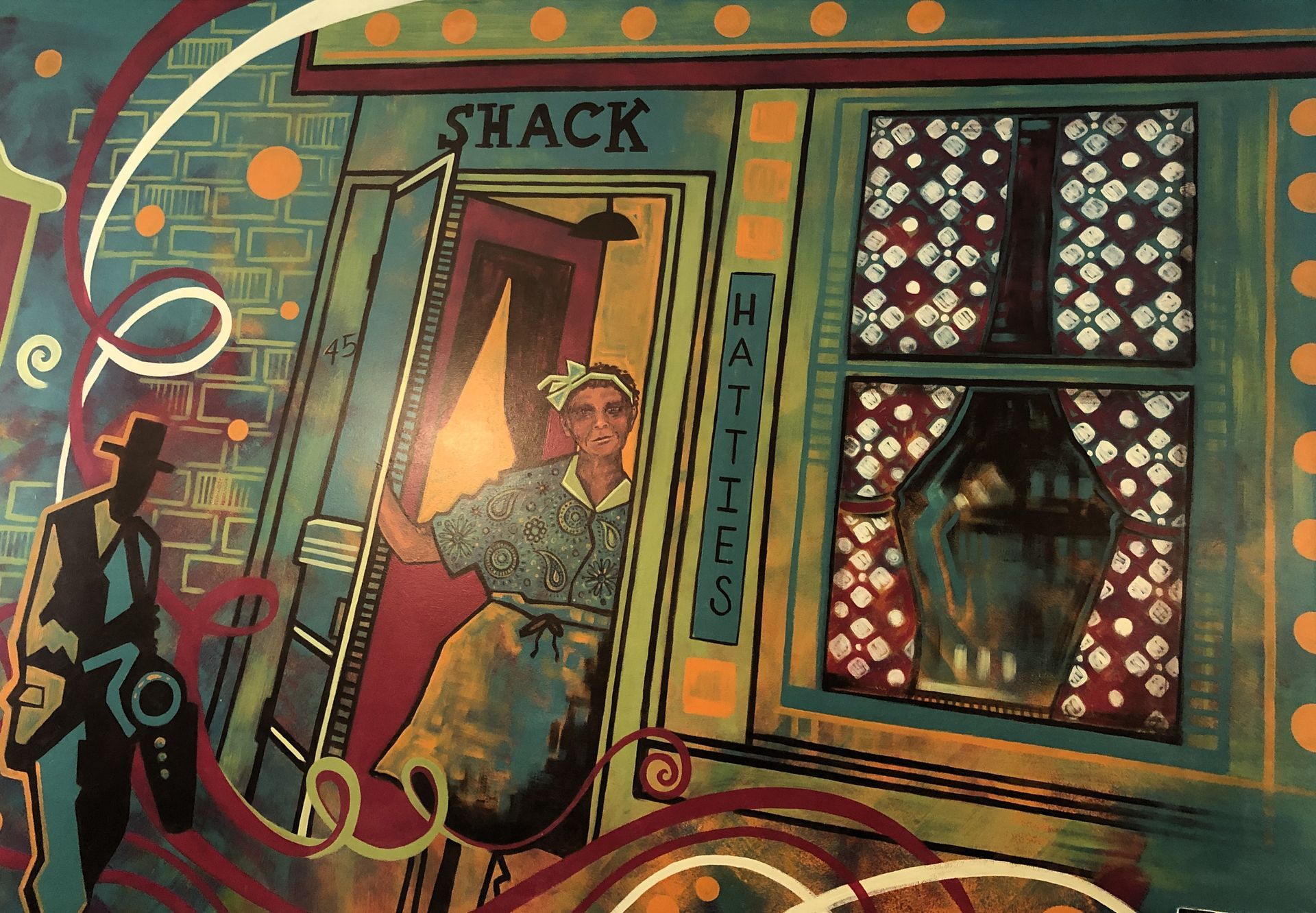 A mural depicts a person in an apron standing in the doorway of Hattie’s Shack, beside a stylized figure in a hat.