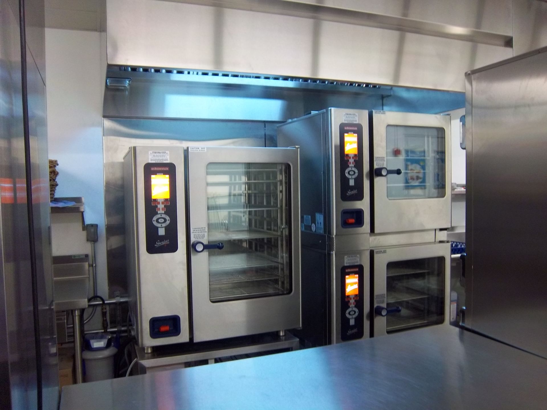 Professional kitchen featuring two commercial Rational brand combination ovens under a stainless steel ventilation hood.