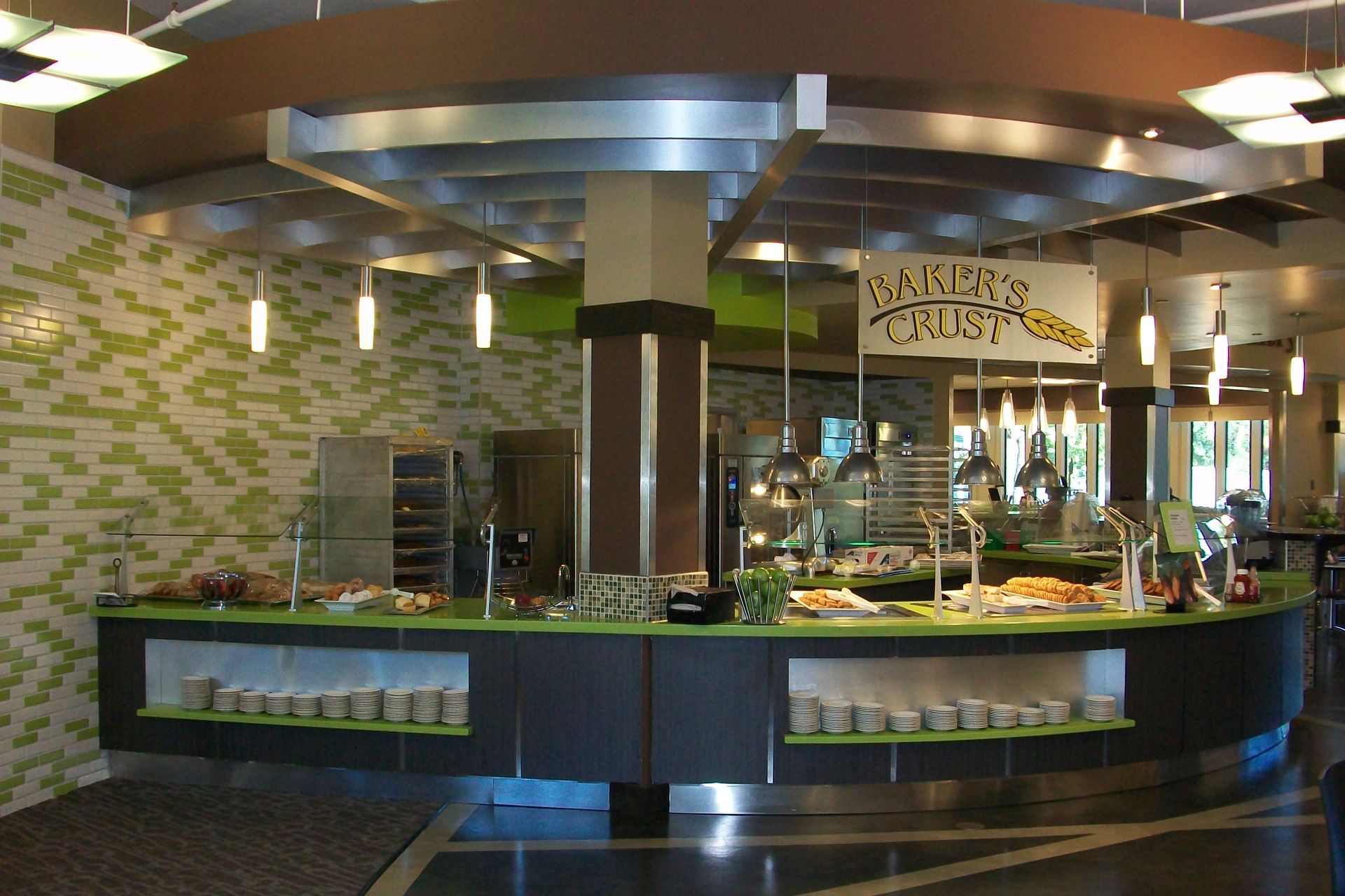 A modern, curved dining station with a black counter, lime green accents, and a sign labeled 