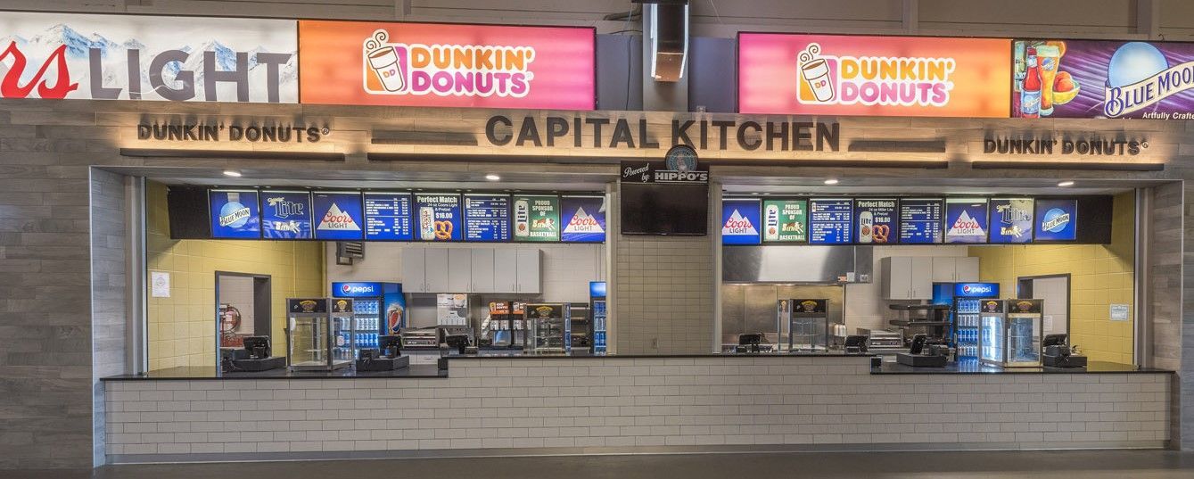 Capital Kitchen concession stand featuring Dunkin' Donuts signage, menu boards, and order counters.