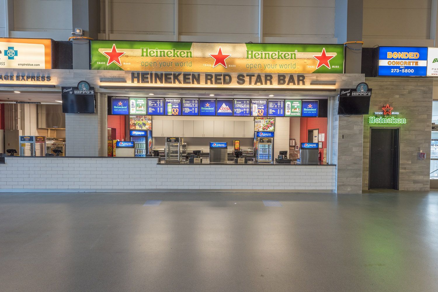A Heineken Red Star Bar concession stand at an indoor arena with a large menu board and a polished gray floor.