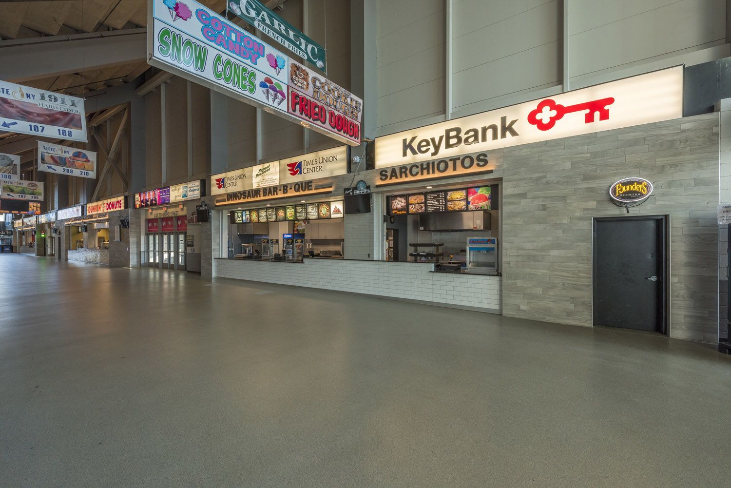 An empty indoor stadium concourse featuring a line of food concession stands, including one sponsored by KeyBank.