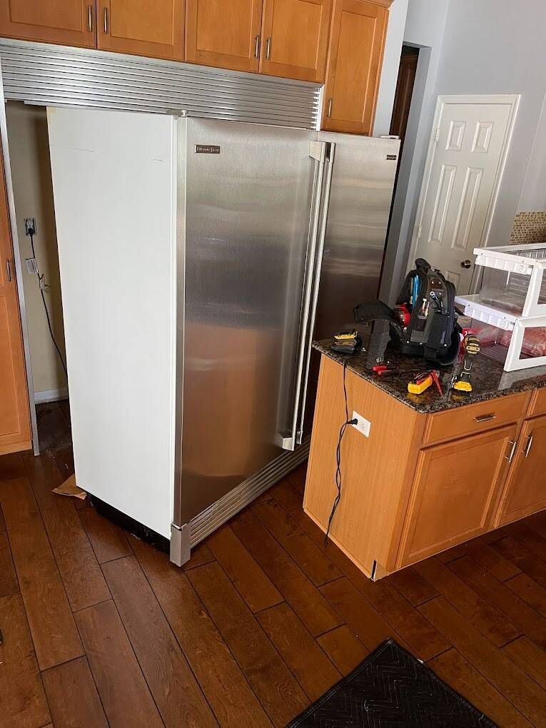 a stainless steel refrigerator is sitting in a kitchen next to a wooden cabinet .