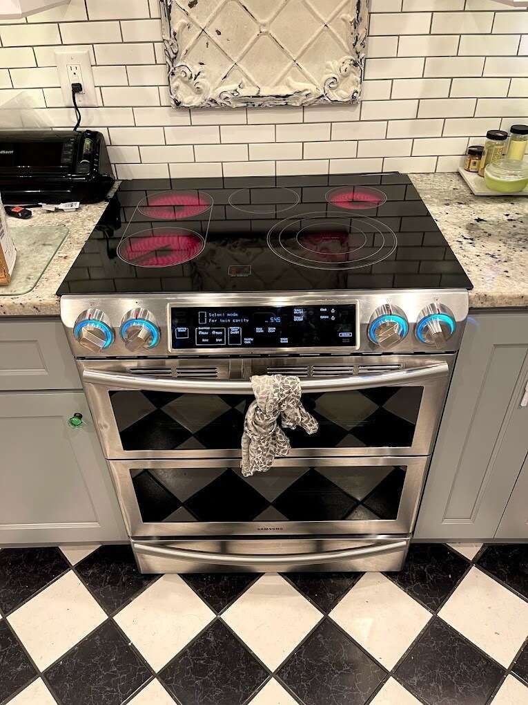 a stainless steel stove top oven is sitting on top of a checkered floor in a kitchen .