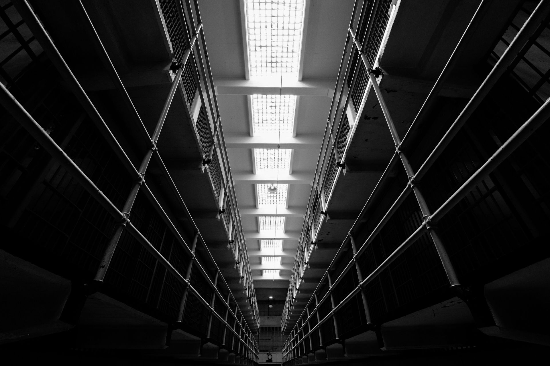 Dimly lit futuristic corridor with bright overhead lights and dark walls leading into the distance