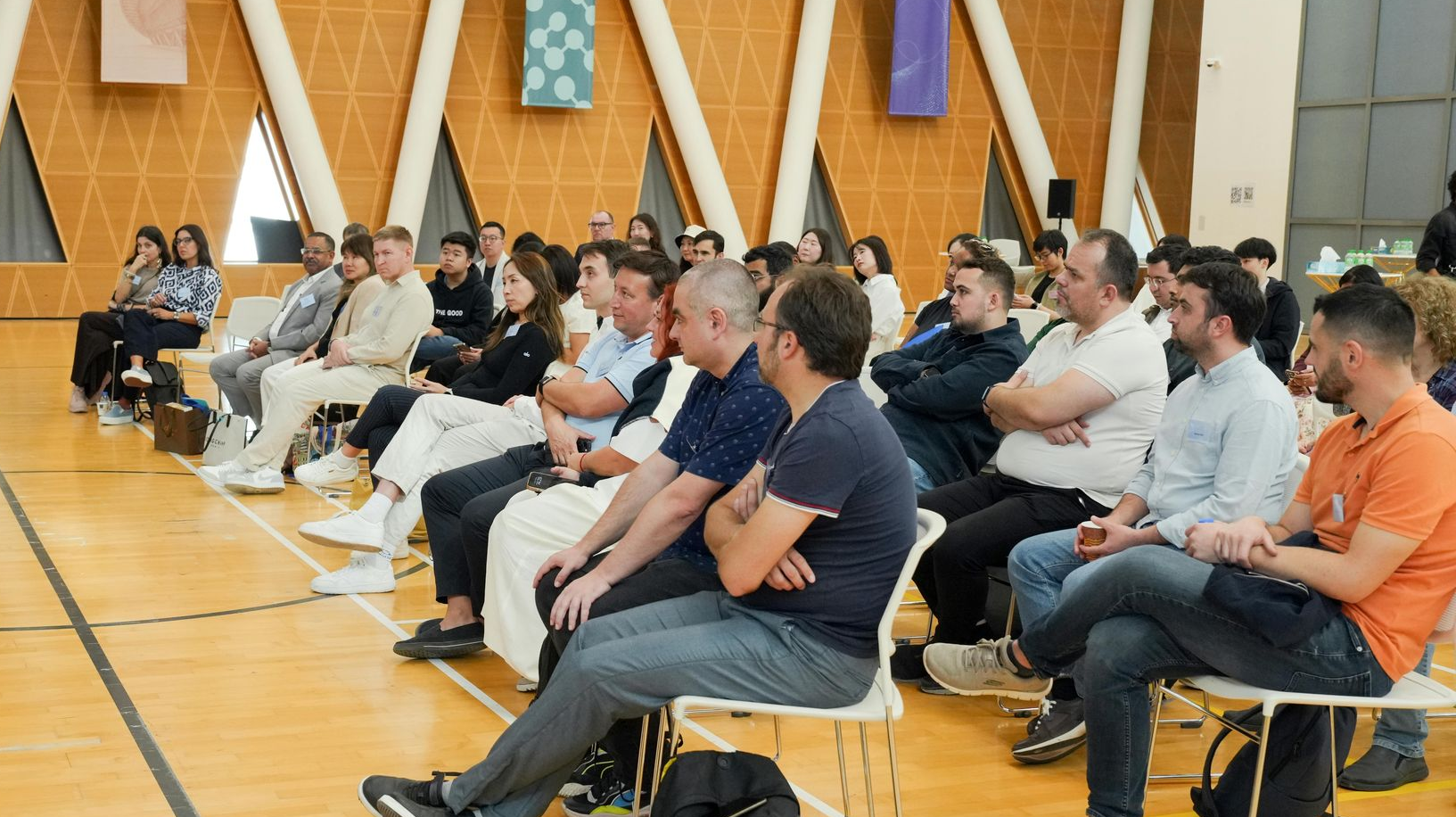 Audience seated in a gymnasium, watching an event.