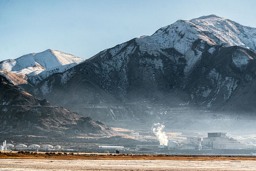 Snowy mountains behind a misty valley with a small plume of steam near the ground