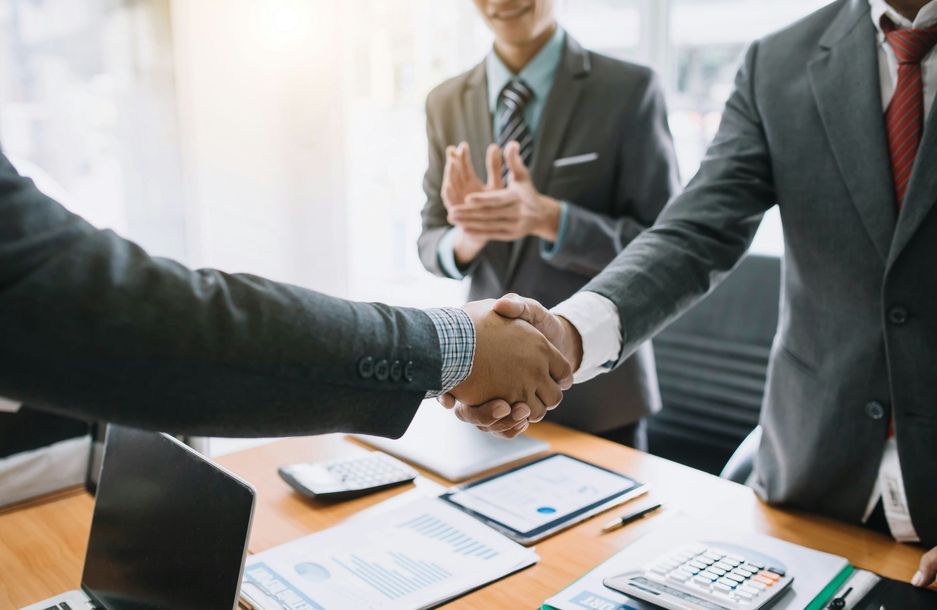 Businesspeople shaking hands across a conference table in a bright office