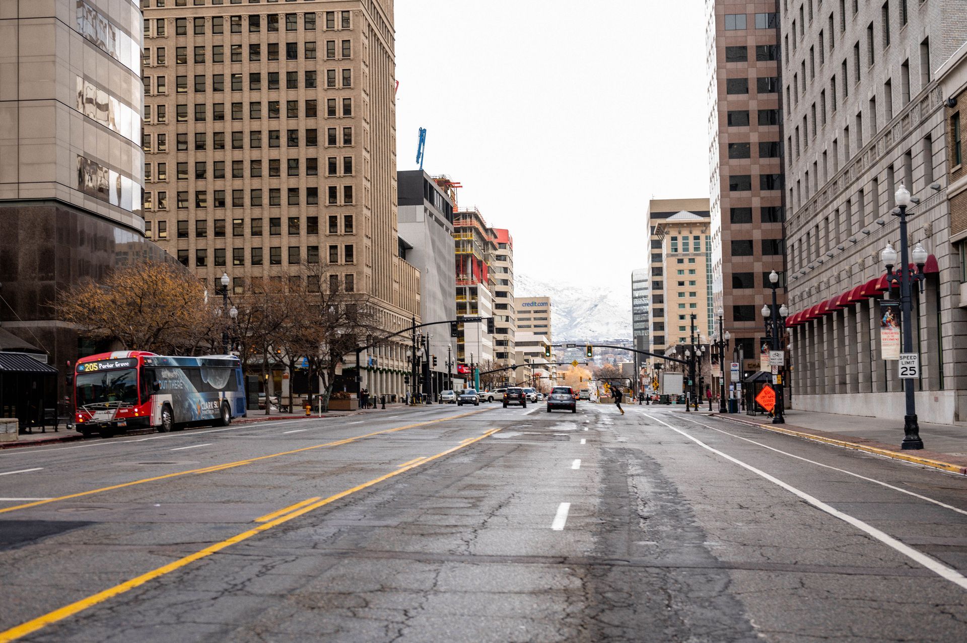 Empty city street with buses, tall buildings, and a wet road on an overcast day