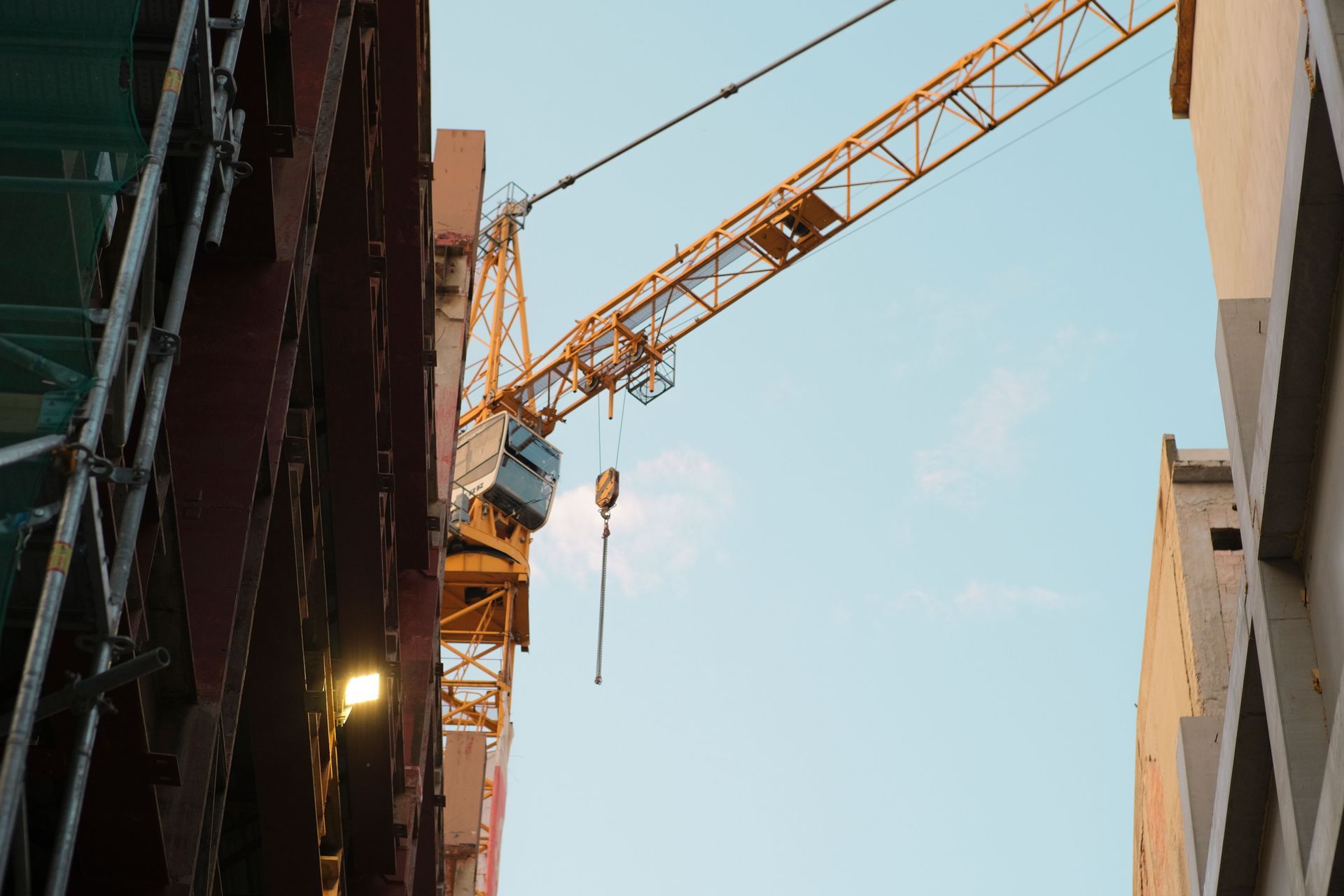 Construction crane between tall buildings against a blue sky