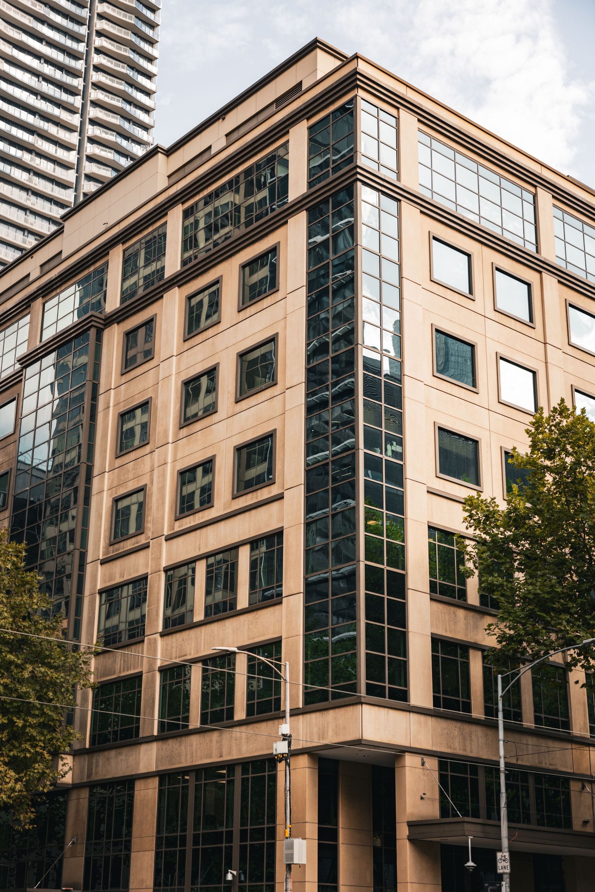 Tall beige office building with green-trimmed windows on a city street