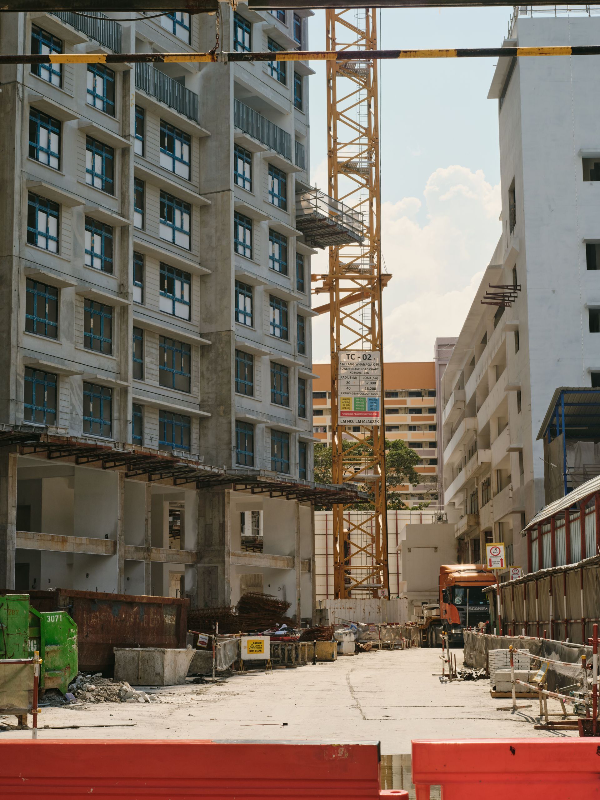 Construction site between apartment buildings with a crane and workers in the foreground