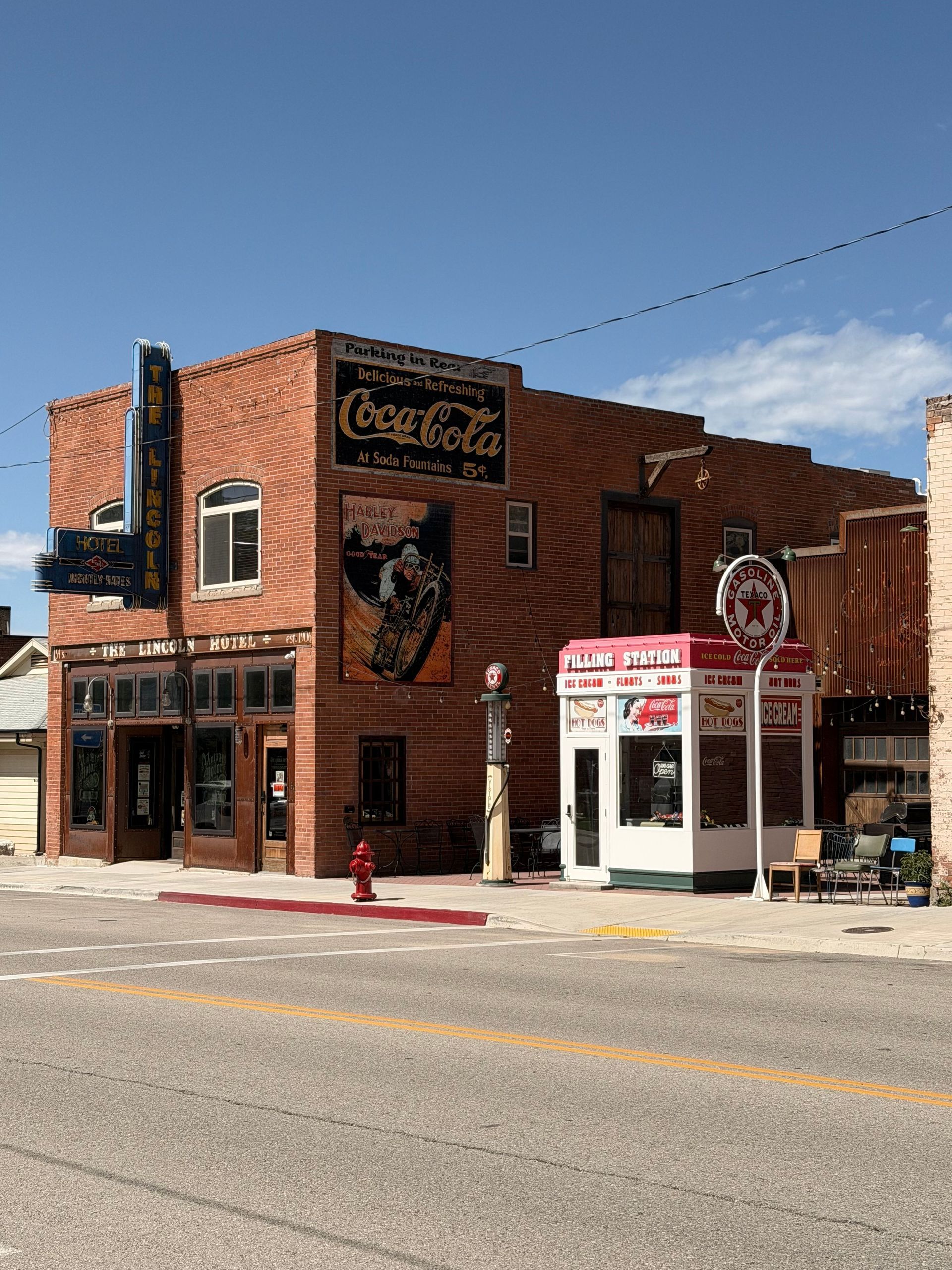 Brick corner building with signs and a white storefront under a clear blue sky.