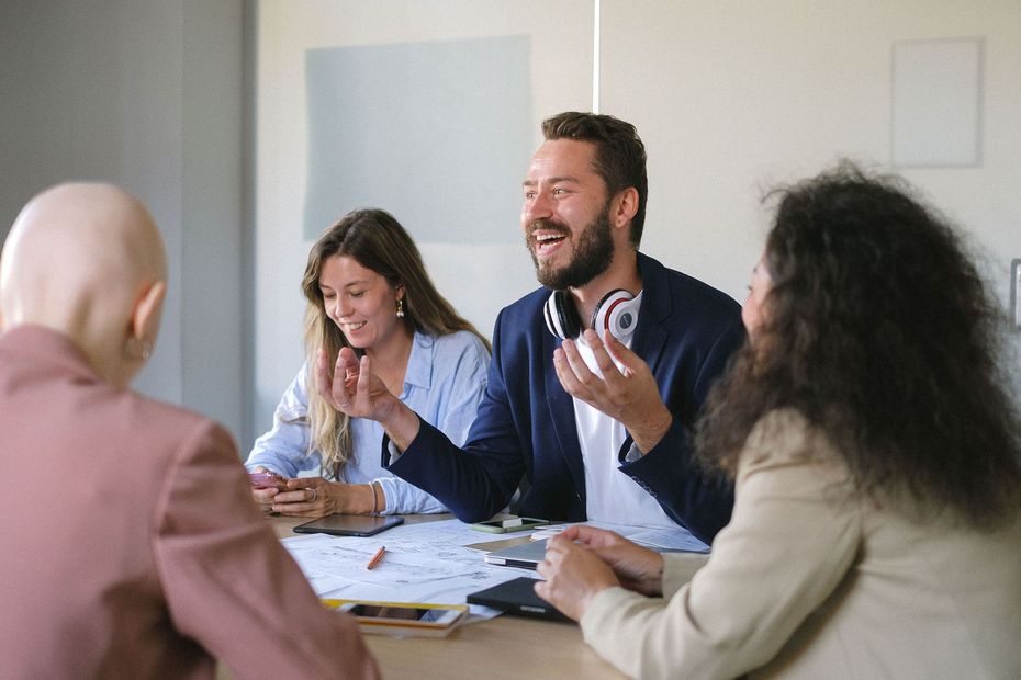 Team meeting at a table, with people smiling and discussing documents in a bright office