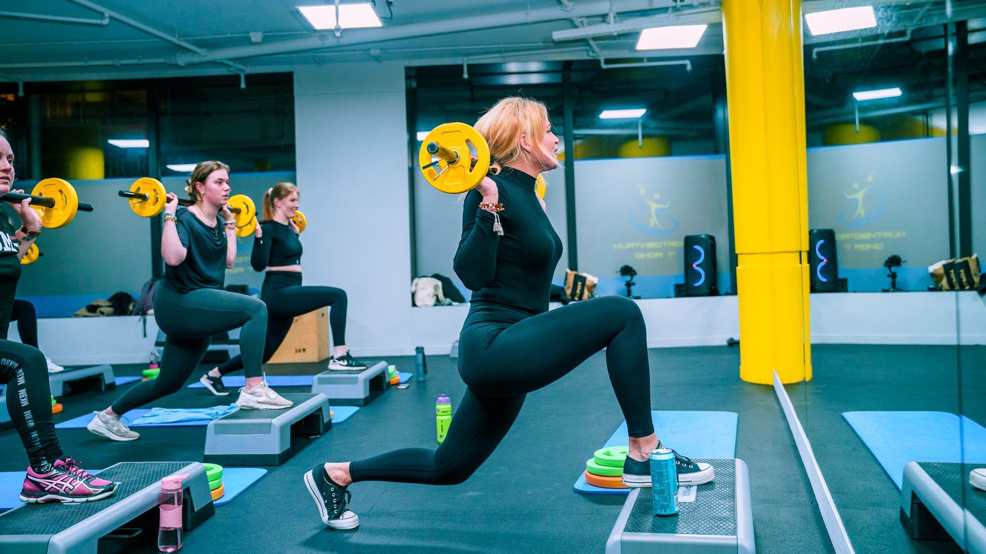 Vrouwen die in een sportschool gewichten tillen en lunges op een trap uitvoeren.