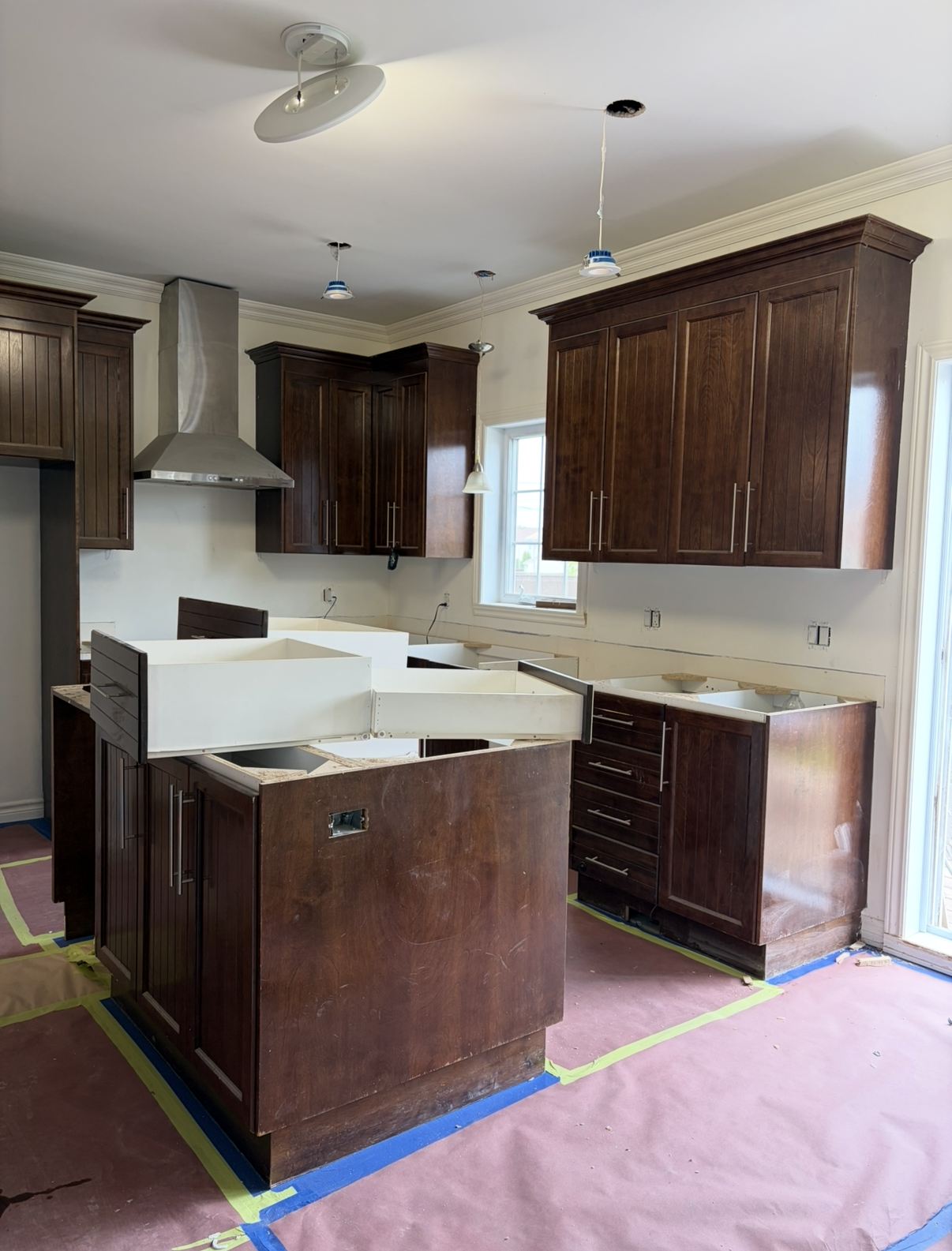 Kitchen under renovation with dark wood cabinets, island, and covered floor