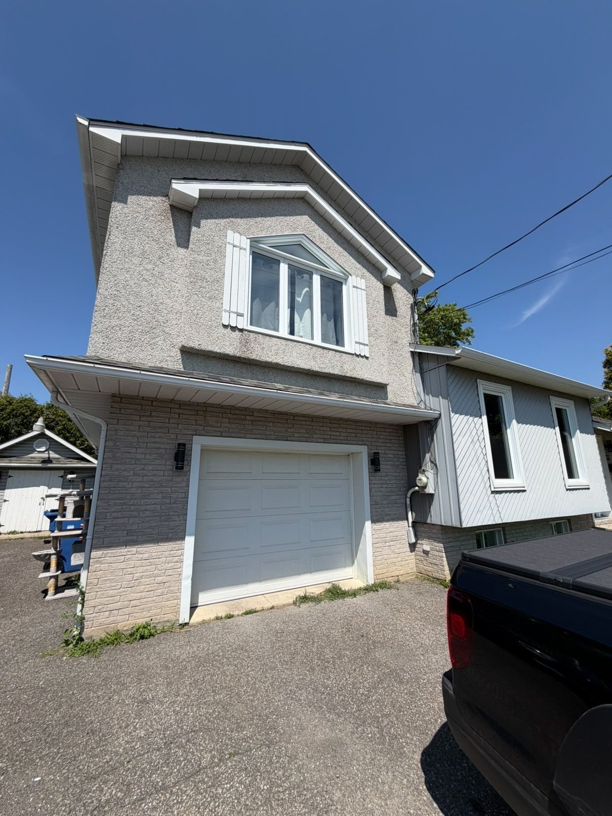 Exterior of a two-story gray house with a white garage door and black car in front