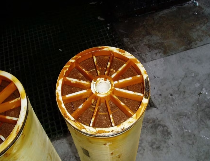 Dos cartuchos cilíndricos de filtración de agua, teñidos de color marrón anaranjado.