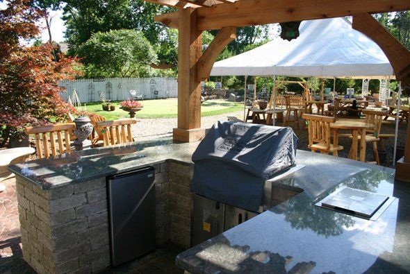 Nice outdoor kitchen with tables and seats in front — Clarkston, MI — Lowries Landscape Inc