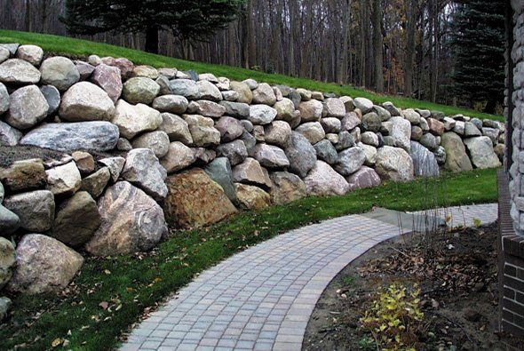 Stone retaining wall with a paved path winding alongside it.