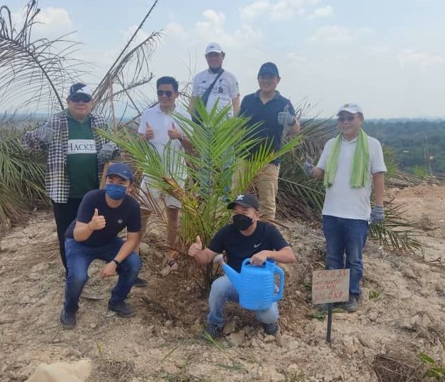 A group of men are standing around a tree and one man is watering it