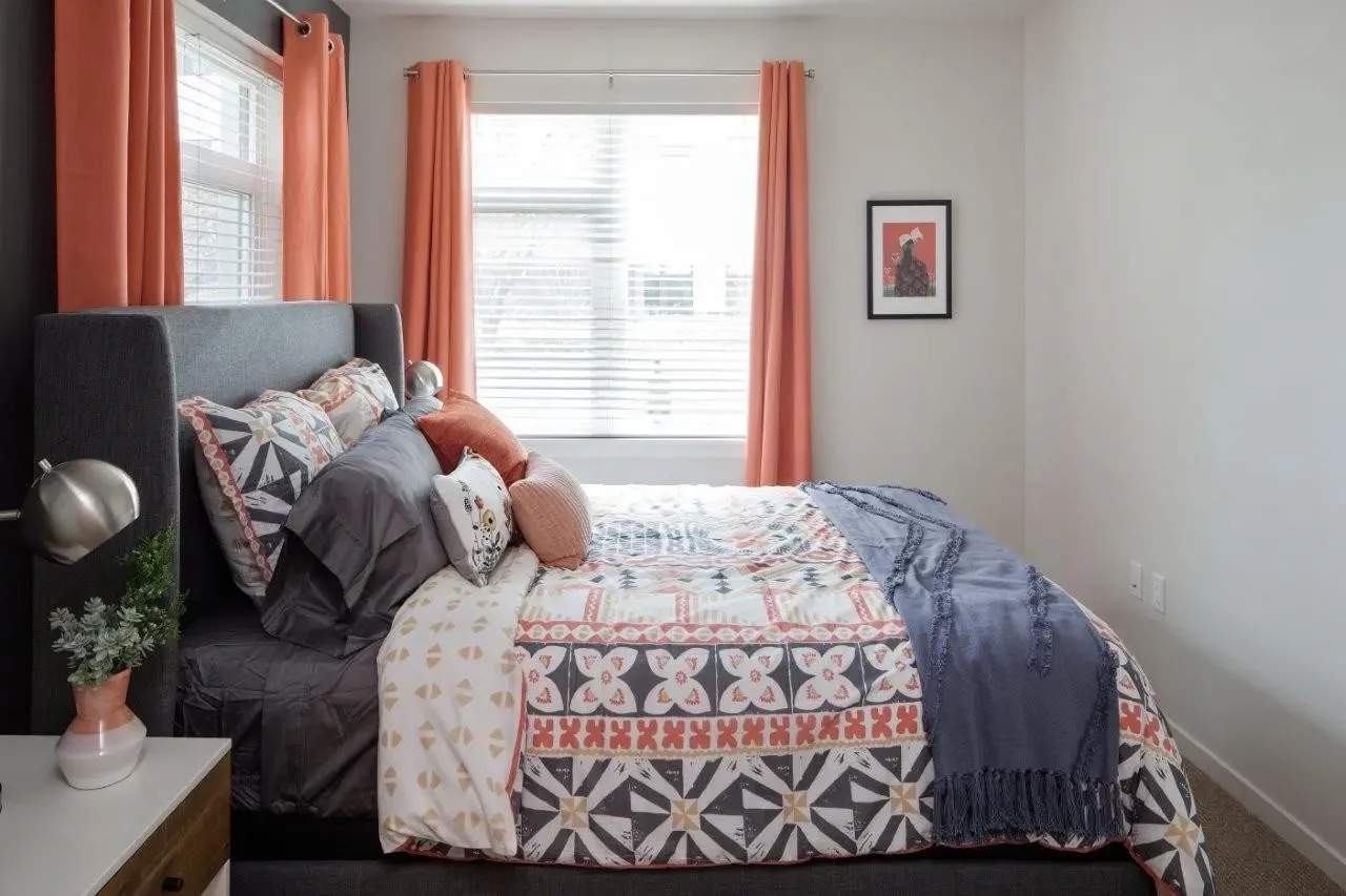 Bedroom with a king-size bed, patterned comforter, and coral curtains.