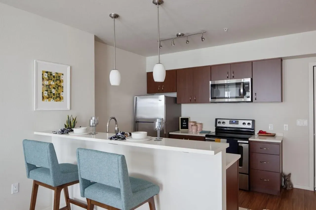 Modern kitchen with island seating, stainless steel appliances, and dark wood cabinets.