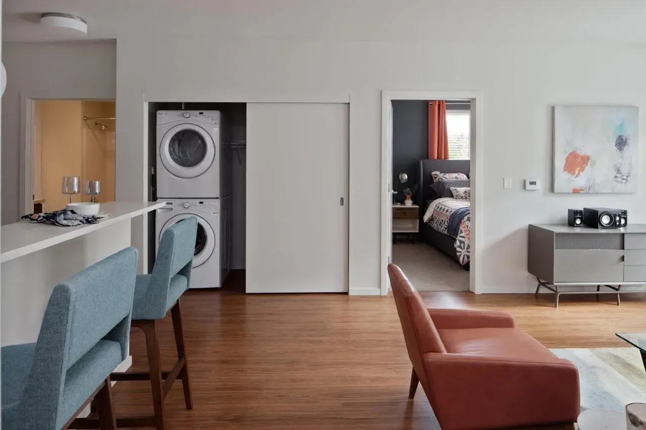Stackable washer and dryer in a hallway closet with a white sliding door.