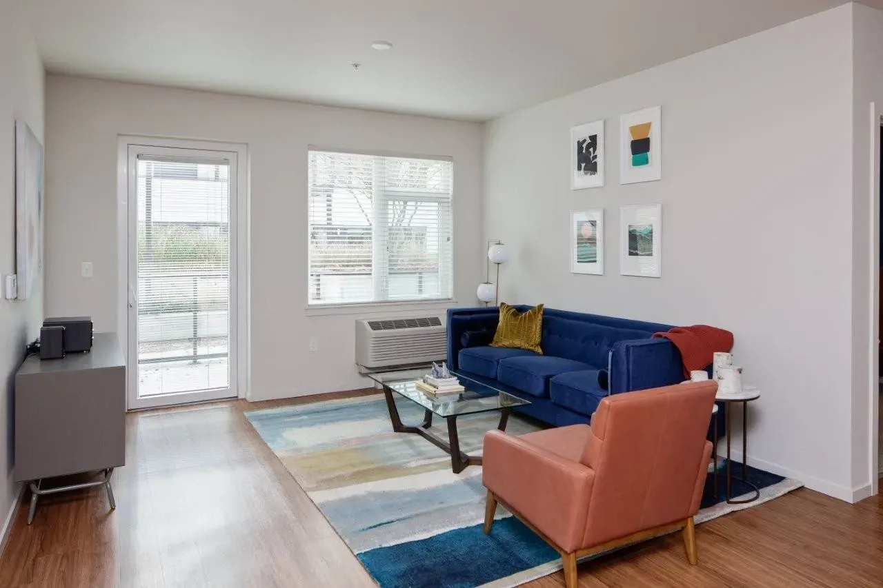 Living room with blue sofa, armchair, coffee table, and access to an outdoor patio.