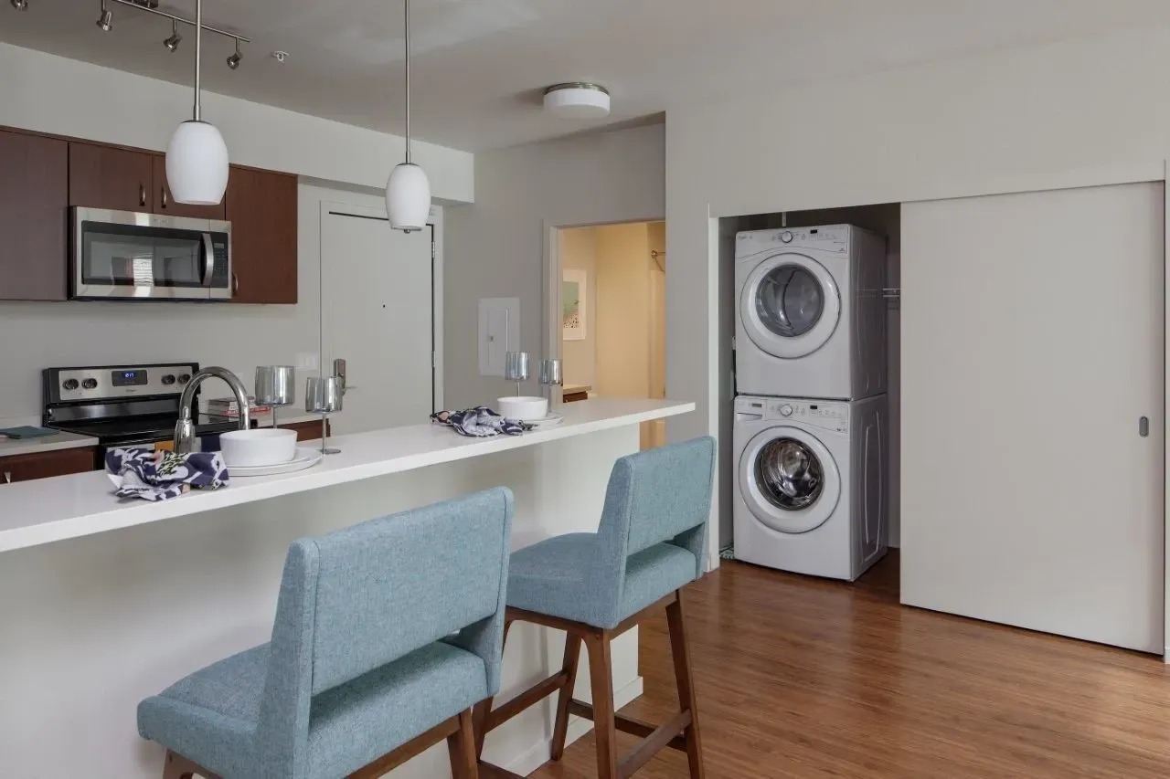 Kitchen with a breakfast bar, two stools, and a stackable washer and dryer.