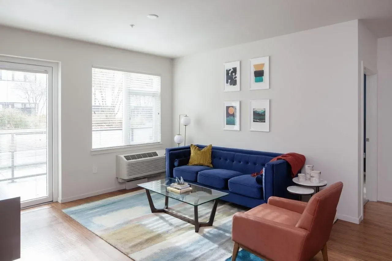 Living room with blue sofa, accent chair, coffee table, and artwork.