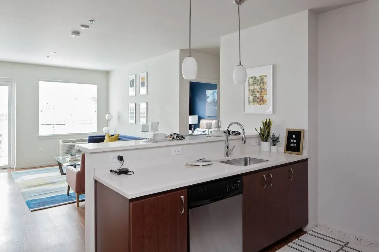 Modern kitchen area with dark wood cabinets, stainless steel dishwasher, and granite countertops.