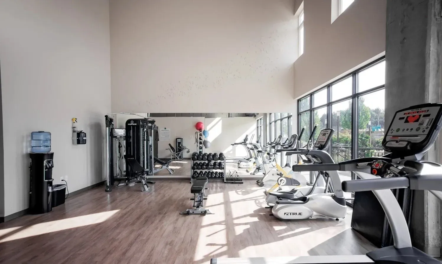 Gym with cardio machines, weight racks, and a water cooler.