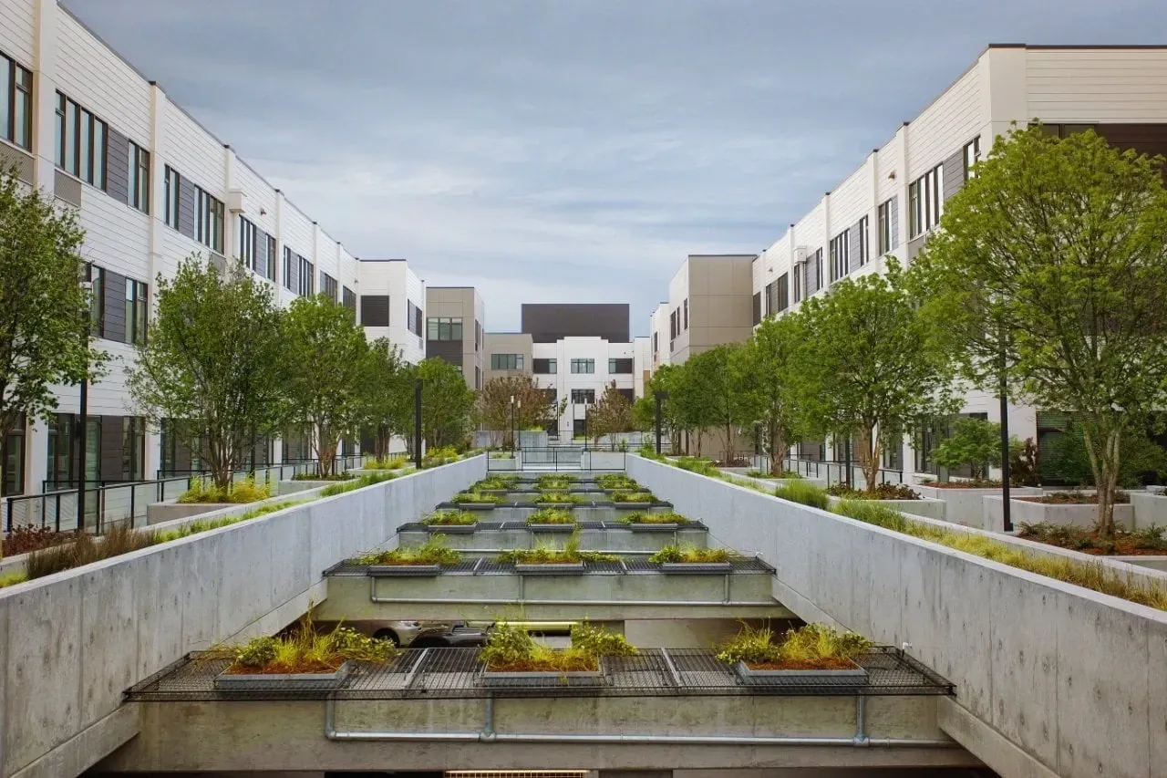 Modern apartment building exterior with a unique terraced courtyard and landscaping.