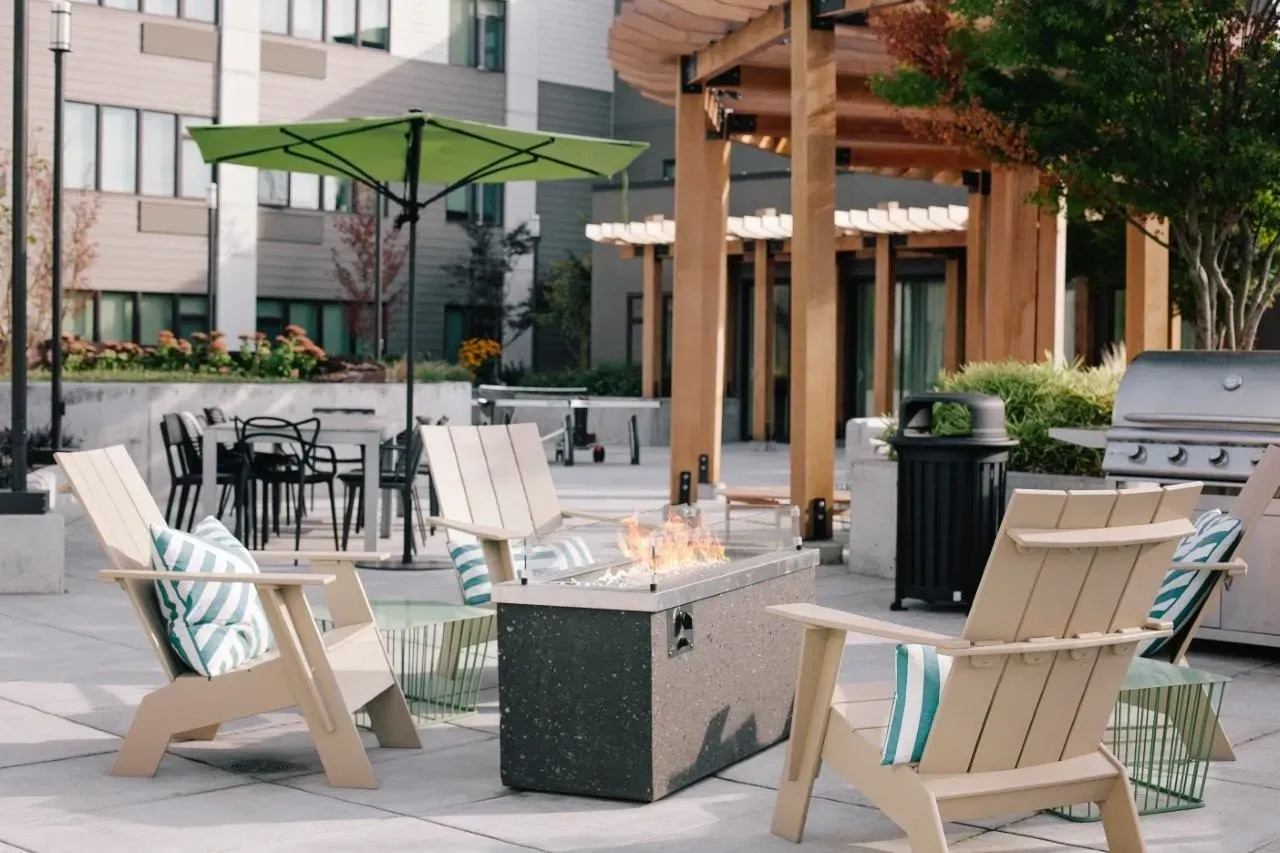 Outdoor lounge area with fire pit, seating, and grills.