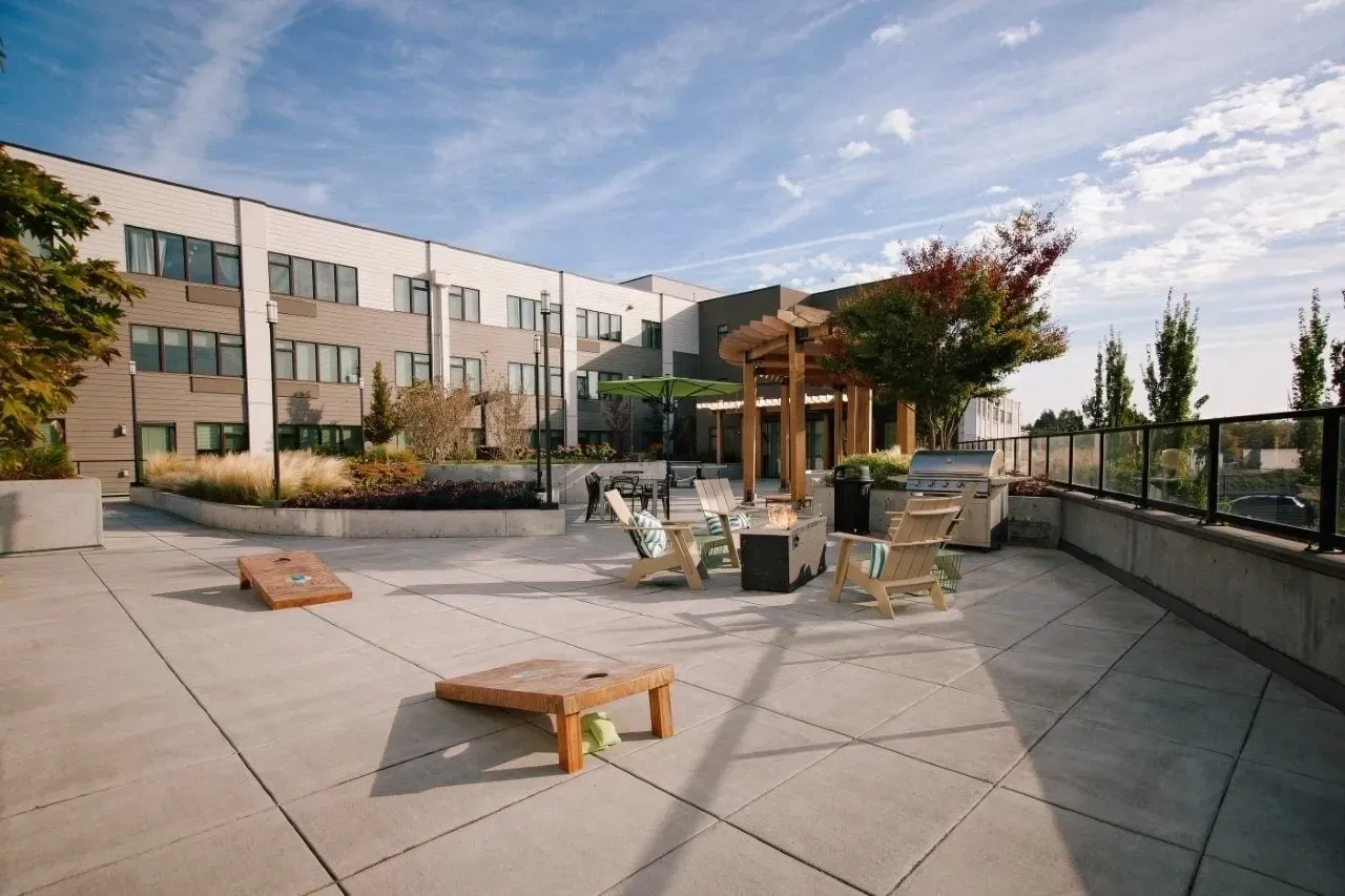 Outdoor patio with seating, fire pit, grills, and cornhole.