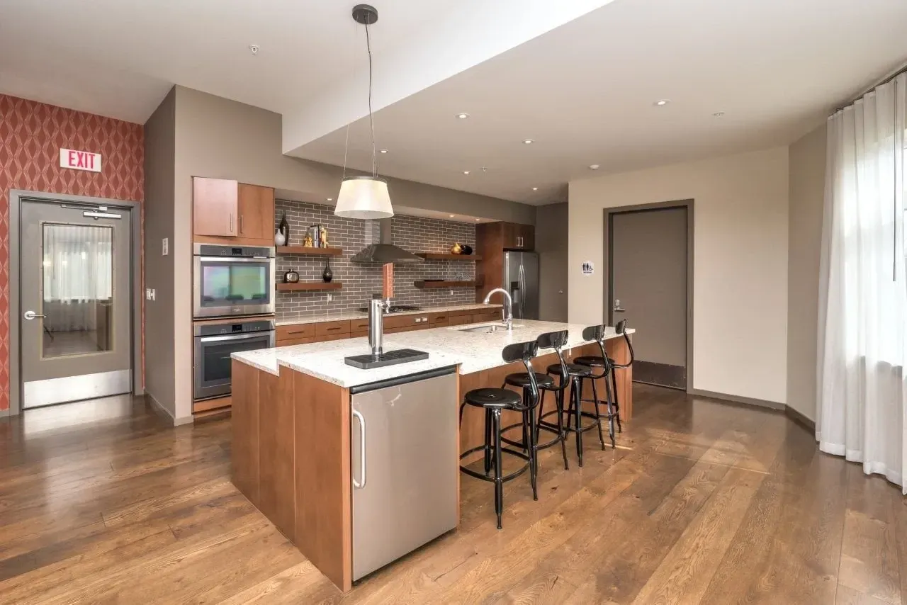 Modern kitchen with island, bar stools, double ovens, and a beer tap.