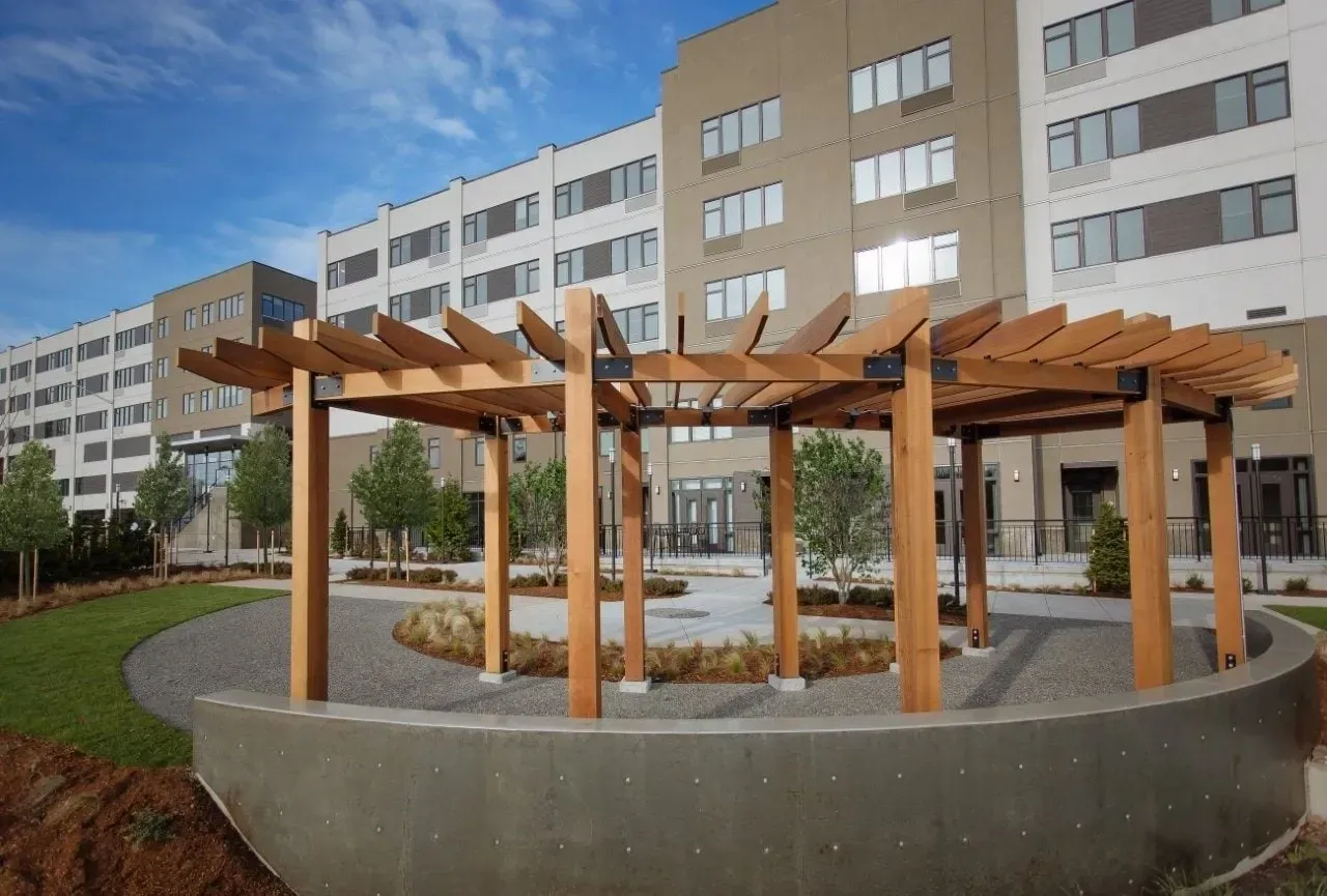 Modern apartment building exterior with outdoor seating area and pergola.