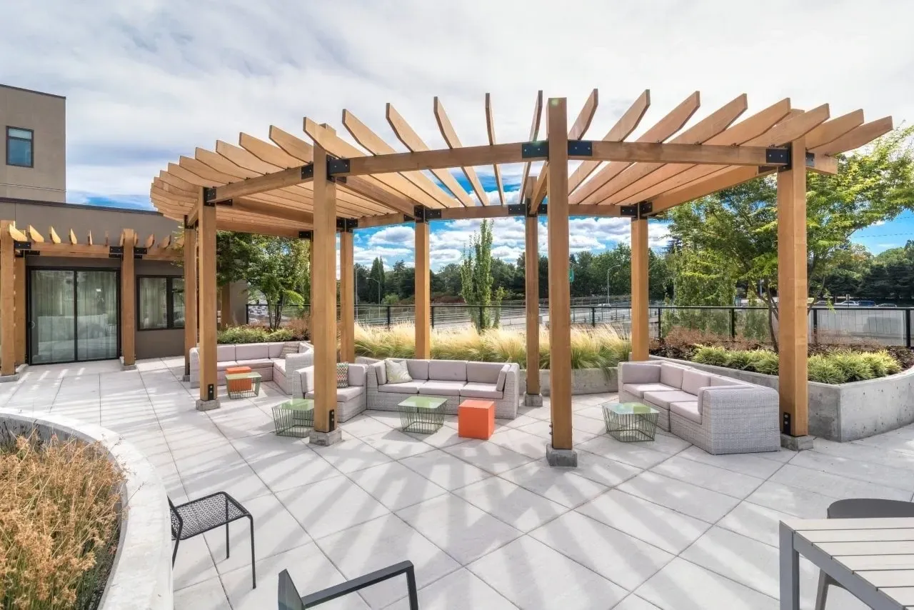 Outdoor patio with a wooden pergola, comfortable seating, and lush landscaping.