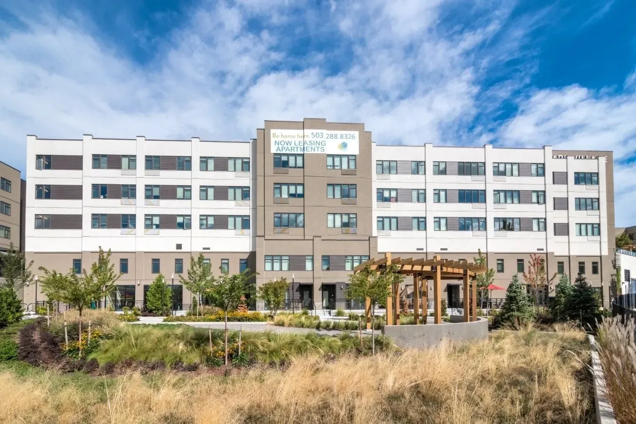 Modern apartment building exterior with landscaping and outdoor seating area.