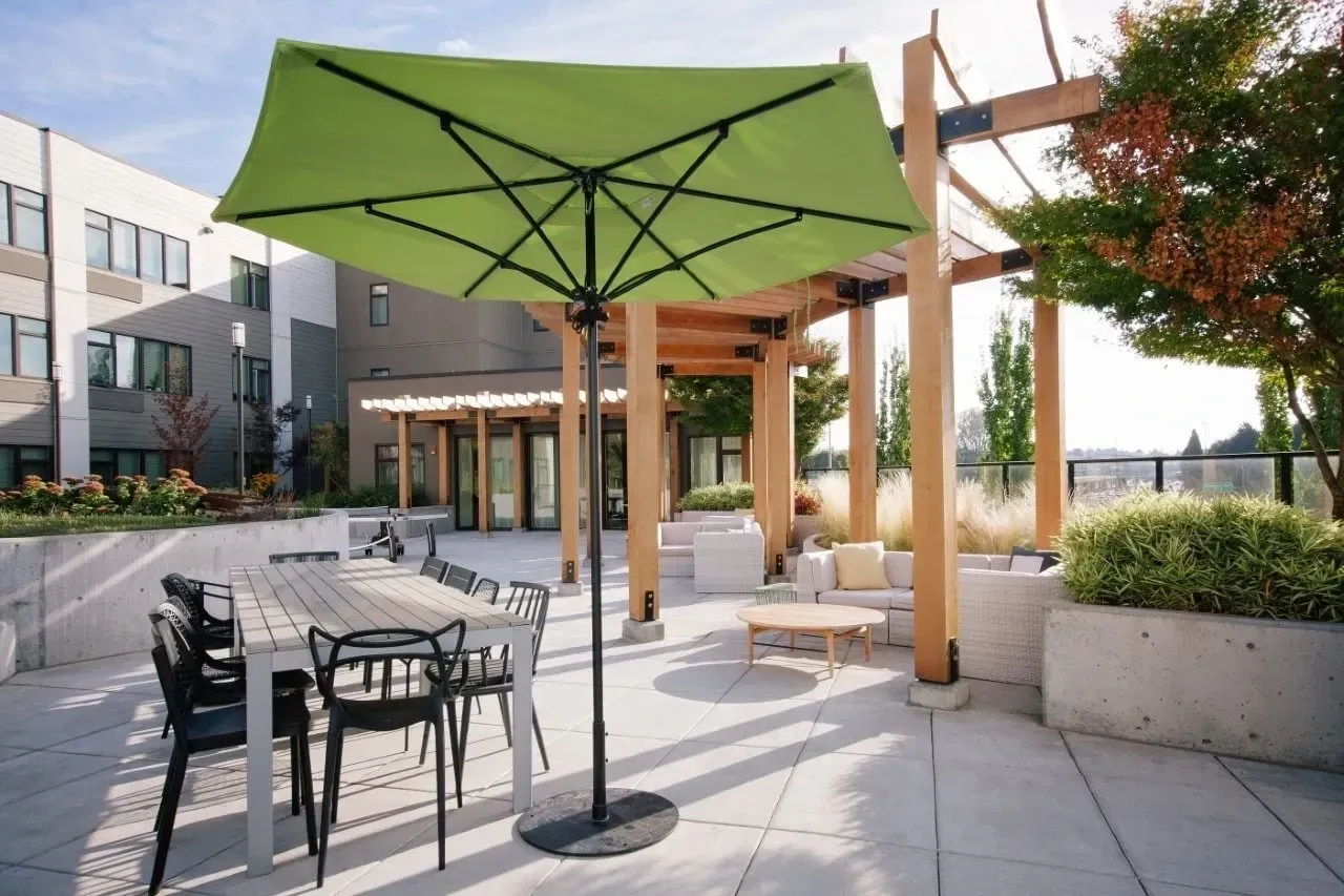 Modern rooftop patio with outdoor dining table, lounge seating, and a green umbrella.