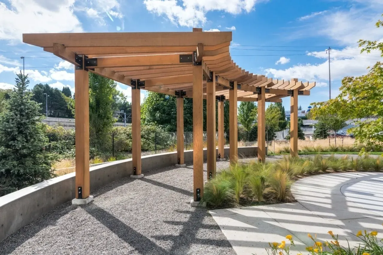 Modern wooden pergola with gravel ground and landscaping.